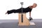 A 50-year-old trainer practices Pilates on an elevator chair, lying on her stomach supporting herself with her arms