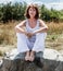 50s yoga woman sitting on stone relaxing for spiritual peace