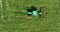 5k A green tractor working in a green meadow. Bird\'s eye view