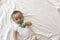 6-8-month-old baby boy lying playfully in bed. Charming 6-7 month little baby in white bodysuit. Baby boy in white bedding. Copy