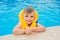 A 6-year blond boy in a life vest at the swimming pool