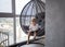 6-year-old boy enthusiastically reads a book, sitting in a swinging hanging chair in a room