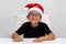 6 year old dark latino boy is ready to celebrate the holidays and write his letter to Santa Claus with Christmas hat
