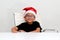 6 year old dark latino boy is ready to celebrate the holidays and write his letter to Santa Claus with Christmas hat