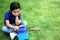 6 year old latino boy sitting on the grass with lunch box and colors for back to school