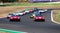 60s vintage race cars large group competition on racetrack, formation lap with