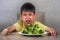 7 or 8 years old upset and disgusted hispanic kid sitting on table in front of broccoli plate looking unhappy rejecting the fresh