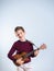 7 year boy playing the ukelele, isolated on gray background