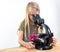 A 7 year old girl looks into an eyepiece of a microscope. Isolated against white background