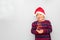 7 year old Latino boy with sweater and Christmas hat, holding Christmas tree with red spheres on gray background