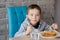 7 years old boy eating lasagne in dining room
