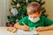 7 years old boy write letter to Santa sitting by desk