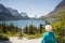 70 year old senior tourist woman looking at mountains and lake scenic view. Enjoying the beauty of nature at Glacier National Park