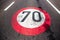 70km/h speed limit sign painted on asphalting road.