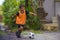 8 or 9 years old happy and excited kid playing football outdoors in garden wearing training vest running and kicking soccer ball