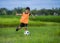 8 or 9 years old happy and excited kid playing football outdoors in garden wearing training vest running and kicking soccer ball