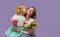 8 march card! Little daughter kisses and hugging her mother with yellow flowers tulip and gift box. Purple studio background. Moth