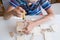 An 8-year-old boy assembles a wooden constructor by himself with a screwdriver. Close-up hands