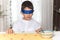 An 8-year-old Caucasian boy sitting at the table at home is blindfolded with a serious gesture.