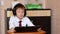 An 8-year-old Caucasian schoolboy in headphones takes part in a videoconference lesson while at home holding a gadget in his hands
