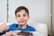 8 year old child holding a spoon with sweet brigadeiro and looking at the camera with a funny face