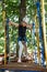 8 years old girl in forest adventure park. Child climb on high rope trail. Outdoor playground with rope way