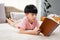 9-year-old Asian boy sitting and reading a book With pleasure, he readily reviewed the things he had learned each day in his bed