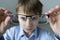 A 9-year-old boy in a blue shirt with glasses checks his eyesight. Dissatisfied with the fact that prescribed glasses -