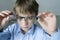 A 9-year-old boy in a blue shirt with glasses checks his eyesight. Dissatisfied with the fact that prescribed glasses -