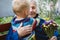 90s years old senior woman great-grandmother hugging great-grandson. Kid boy supporting and giving flowers to great