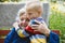 90s years old senior woman great-grandmother hugging great-grandson. Kid boy supporting and giving flowers to great