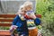 90s years old senior woman great-grandmother hugging great-grandson. Kid boy supporting and giving flowers to great