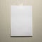 A4 white sheet of paper hanging on a wall glued with a piece of paper tape on a light background