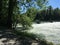 Aare river in riverside forest with high water near weir in summer time