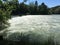 Aare river in riverside forest with high water near weir in summer time