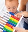 Abacus, math and baby with mom playing, learning and teaching for child development on bed. Bonding, toy and closeup of