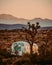 Abandoned airstream on the grassy field surrounded by the mountains in the desert