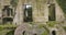 Abandoned ancient stone water mill building with growing vegetation detail on a sunny day