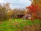 Abandoned autumn garden with a barn. Colorful vegetable garden near the village house on an autumn day