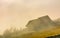 Abandoned barn on hillside in fog at sunrise