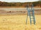 Abandoned beach at empty pond with old blue kids slide above muddy place and dirty beach sand. Autumn melancholic atmosphere.