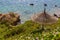 Abandoned beach. Straw sun umbrella in the wild rocky terrain. Overgrown loach beach. The sea coast where no one has been resting