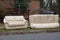 Abandoned beige couches on the grass by a curb in front of a house waiting to be removed on trash day