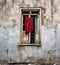 Abandoned brick building with a red cloth draped over a window, giving a desolate atmosphere