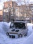 abandoned broken car in winter buried under a snowdrift in the parking lot