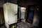 Abandoned building interior with the broken refrigerator, a doorway and garbage