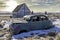 Abandoned car and church on a hillside overlooking twin grain elevators in Neidpath, SK