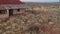 Abandoned car wreck outside an old abandoned building with rusted red roof Aerial video