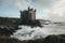 abandoned castle overlooking the sea, with waves crashing against the shore