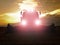 Abandoned combine harvest wheat with lighted main lights in the middle of a farm field. Morning yellow wheat field on the sunset